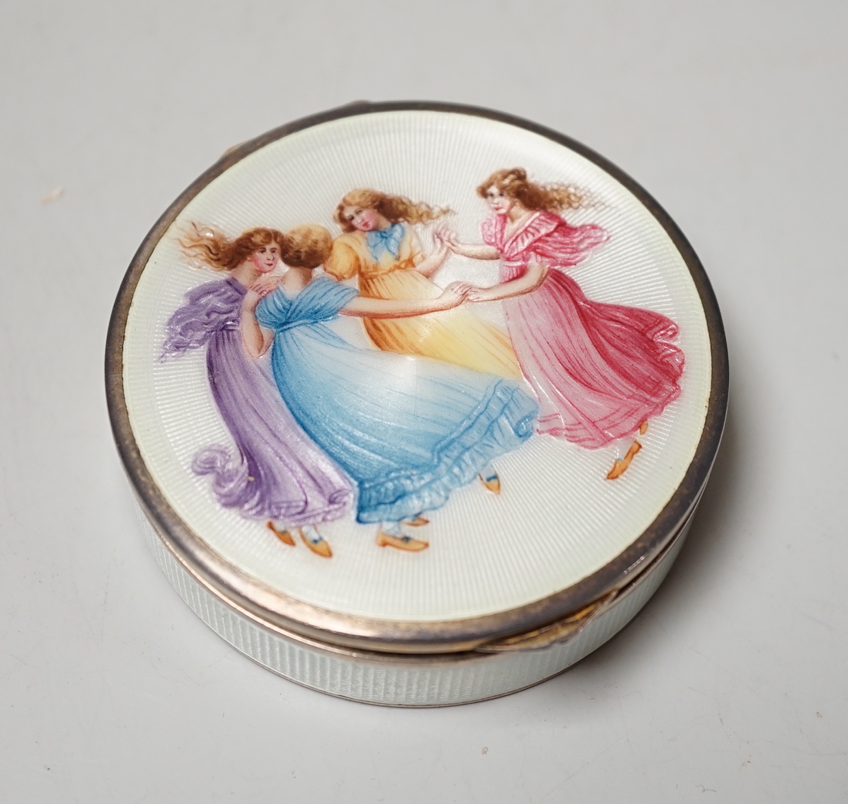 A German silver and enamel circular powder box, decorated with dancing maidens, import marks for Edinburgh, 1952?, 69mm.